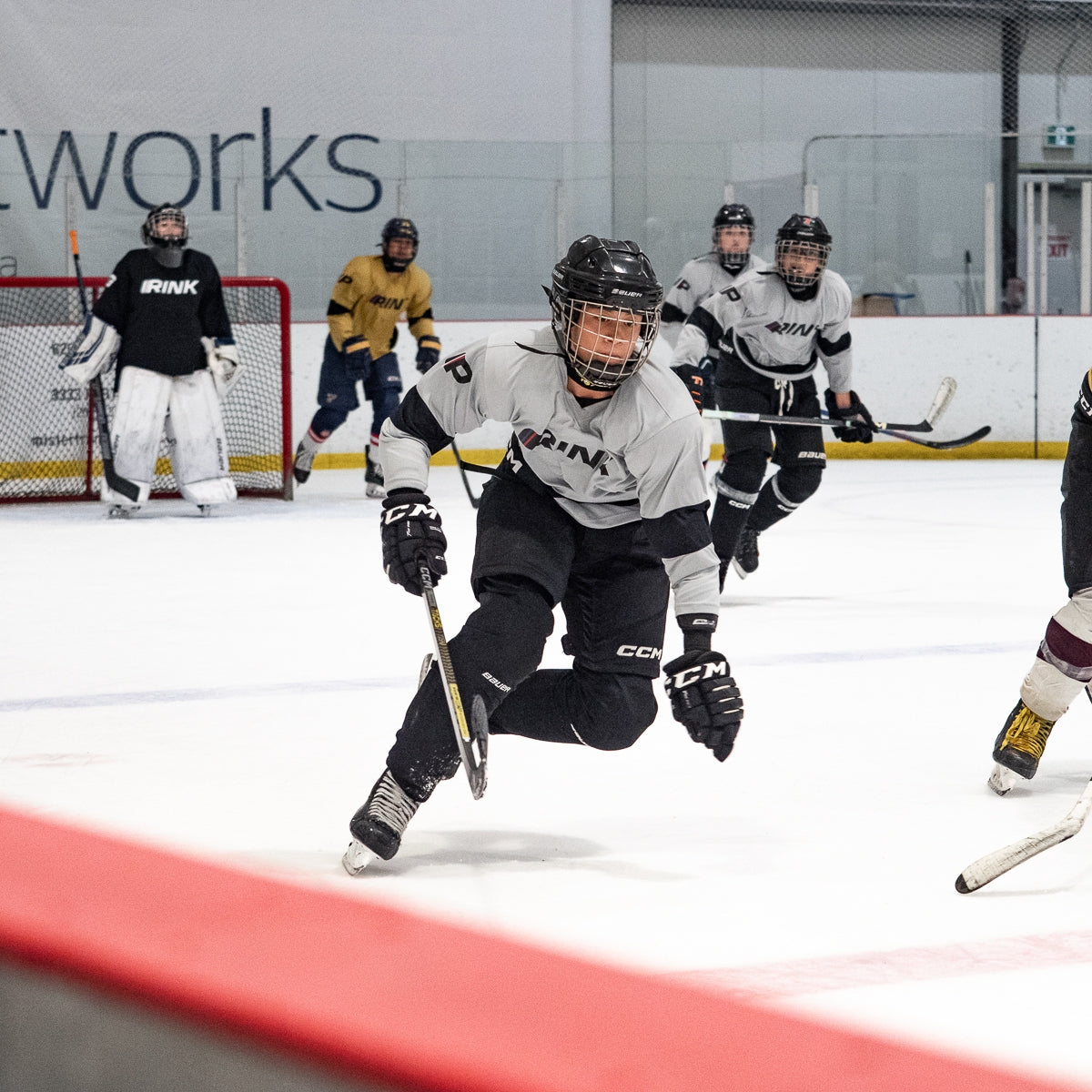 Hockey player in action on an ice rink with 'INK' branding.